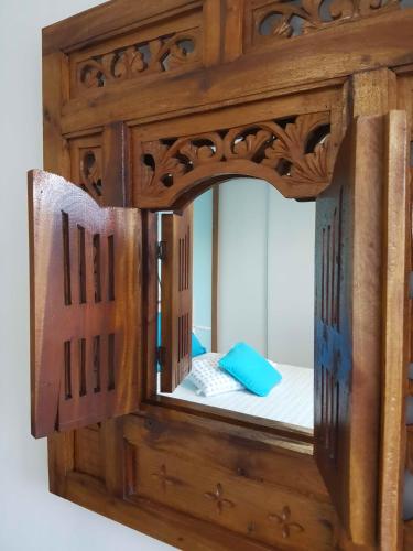 a wooden mirror with a bed in a room at La Maison des Hôtes in Saint-Joseph