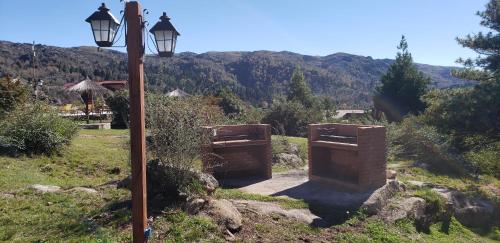 a street light next to a field with a mountain at Aires Serranos - Suites in La Cumbrecita
