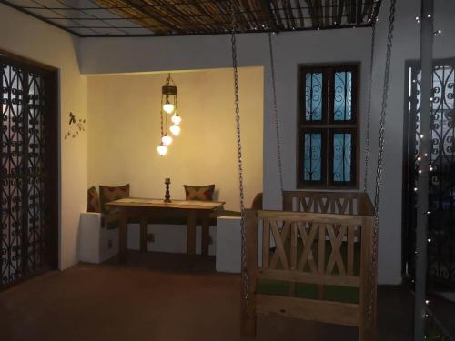 a room with a wooden table and a swing at Dragonfly Cottage in Bagamoyo