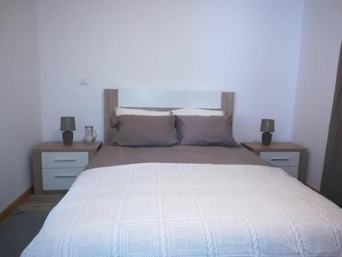 ein Schlafzimmer mit einem weißen Bett und zwei Nachttischen in der Unterkunft Casa das Sereias in Rabo de Peixe