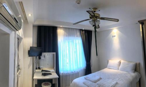 a bedroom with a bed with a ceiling fan and a window at Görkemli Hotel in Istanbul