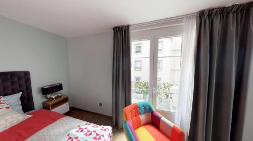 a bedroom with a bed and a chair and a window at Appartement cosy au cœur de Grenoble avec Parking gratuit in Grenoble