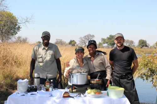 a group of people standing around a table with a pot at Nkasa Lupala Tented Lodge in Sangwali