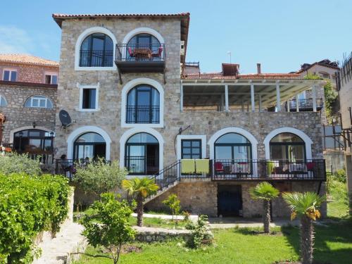 uma antiga casa de pedra com uma varanda e palmeiras em Apartments Susanna em Ulcinj