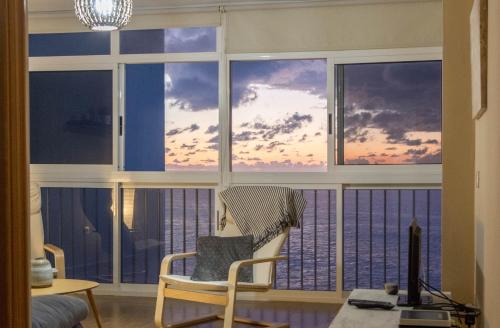 una silla frente a una ventana con vistas al océano en Acogedor apartamento con vista al mar, en Tacoronte