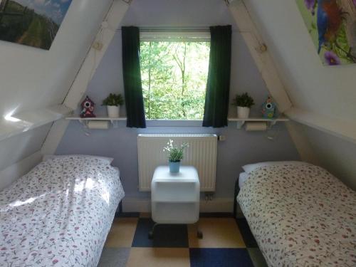 Dos camas en una habitación pequeña con ventana. en Sunclass Durbuy Huisje 132, en Durbuy