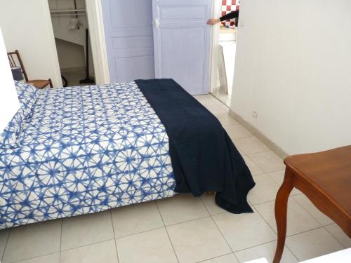 a bed with a blue and white comforter in a room at appartement de la callade in Peyriac-de-Mer