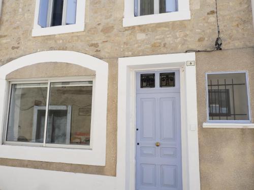 una casa con una puerta azul y dos ventanas en appartement de la callade en Peyriac-de-Mer