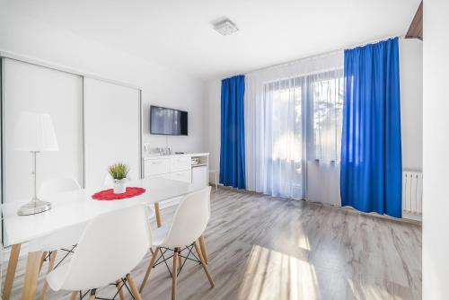 a white dining room with blue curtains and a white table and chairs at Villa Azalia in Jastrzębia Góra