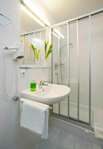 a white bathroom with a sink and a shower at Gasthof Lerner in Freising