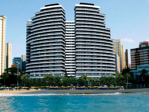 two tall buildings with umbrellas in front of a beach at LANDSCAPE SOLAR - Beira Mar de Fortaleza in Fortaleza