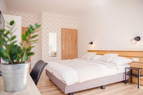 a bedroom with a white bed and a potted plant at Penzion Albrechtt in Kežmarok