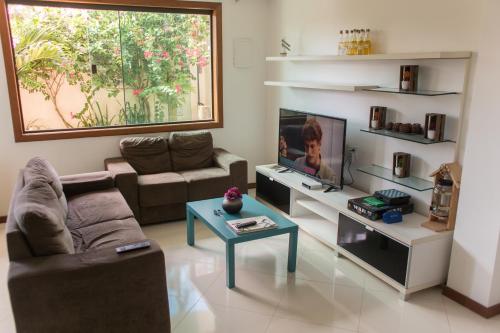 a living room with a couch and a tv at Enseada Hostel in Arraial do Cabo