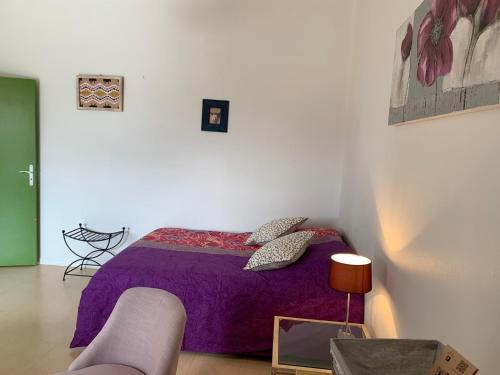 a bedroom with a purple bed and a couch at Studio coeur historique Albigeois in Albi