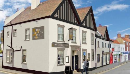 a white and black building on the corner of a street at The George Inn in Barton-upon-Humber