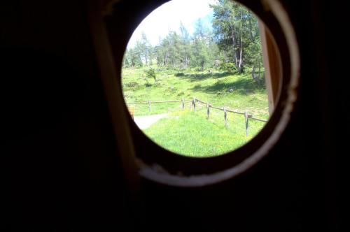 a view of a field through a round window at Lärchenhütte in Tauplitzalm
