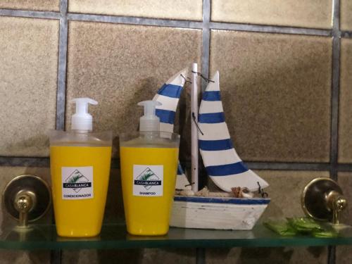 two bottles of orange juice sitting on a shelf with a boat at Hotel Casablanca in Pipa