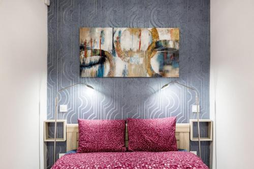 ein Schlafzimmer mit einem rosa Bett mit einem Gemälde darüber in der Unterkunft Quiet nest in the bustling centre of Budapest in Budapest