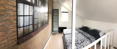 a bedroom with a bed and a brick wall at Logies het Noordwestertje in Den Burg