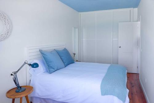 1 dormitorio con 1 cama con almohadas azules y lámpara en Hola ola Bajamar en Bajamar