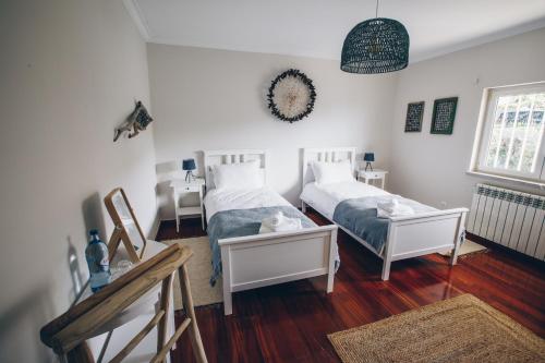 Habitación con 2 camas, paredes blancas y suelo de madera. en Sunny Soul, en Malveira da Serra