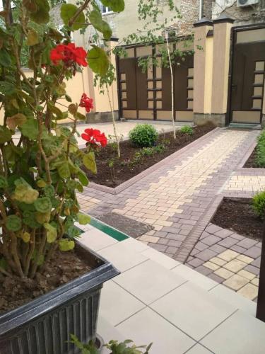 a garden with red flowers and a brick walkway at MEDI Guest House in Osh