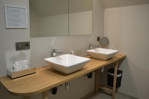 a bathroom with two white sinks on a wooden counter at B&B Allegambe's Goed in Zedelgem