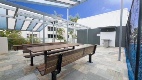 - une terrasse avec bancs en bois au-dessus d'un bâtiment dans l'établissement Monterey Lodge Unit 16 27 Warne Terrace Kings Beach, à Caloundra
