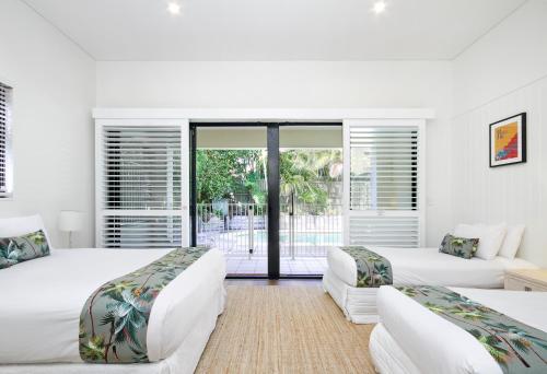 a white bedroom with two beds and a balcony at 1-22 Stevens Street, Sunshine Beach in Noosa Heads