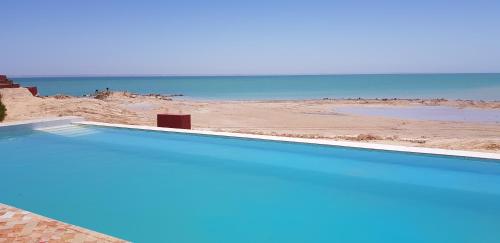 a swimming pool with a beach in the background at Hôtel Calipau Riad Maison d'Hôtes in Dakhla