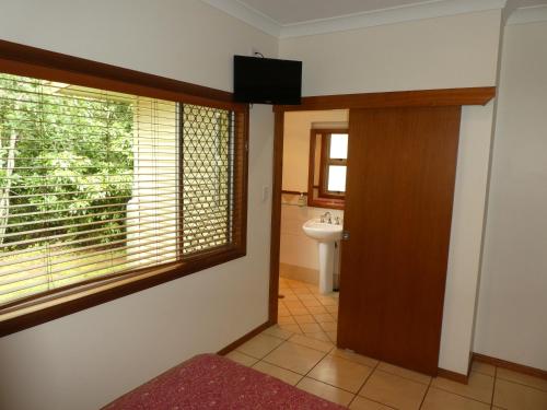 baño con puerta, ventana y lavabo en The Summit Rainforest Retreat, en Atherton