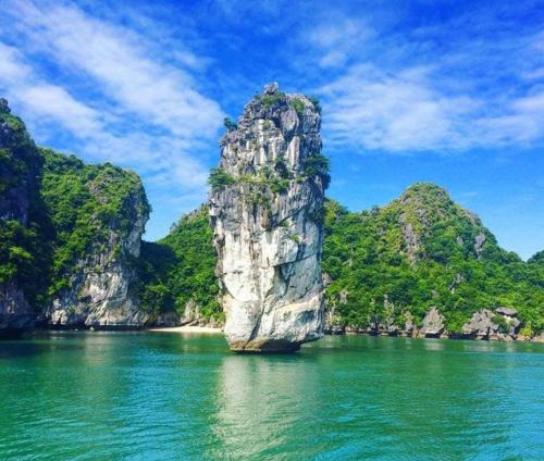 uma grande rocha na água com montanhas ao fundo em Thanh Trung Hotel em Ilha de Cát Bà