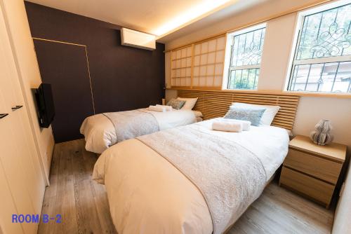 two beds in a small room with two windows at Guest Villa Hakone Yumoto RiverSide in Hakone