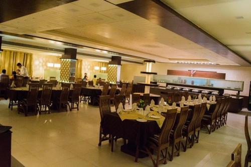 a dining room with tables and chairs and people in a restaurant at Hotel Sheela Shree Plaza in Jhānsi