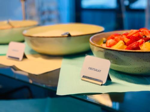 two bowls of fruit sitting on a glass table at Aqua Hotel in Konstanz