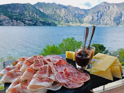 a plate of food with meat and cheese and a drink at Hotel Villa Carmen in Malcesine
