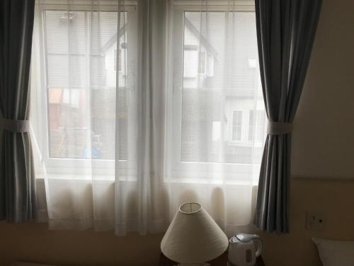 a window with curtains and a lamp in front of it at Petit Hotel Kurumi to Milk in Tateshina
