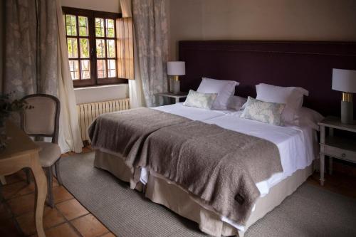 a bedroom with a large bed and a window at Hotel Rural Las Tejuelas in Valdecaballeros
