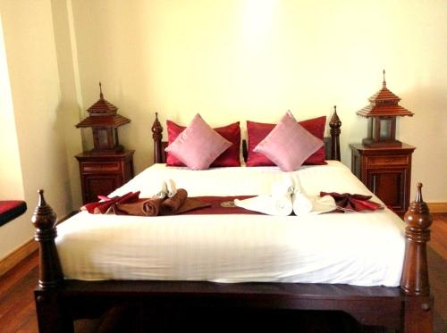 a bedroom with a bed with red and pink pillows at Hua Hin Blue Lagoon in Cha Am