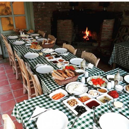 a long table with plates of food and a fireplace at Adatepe Otel in Adatepe