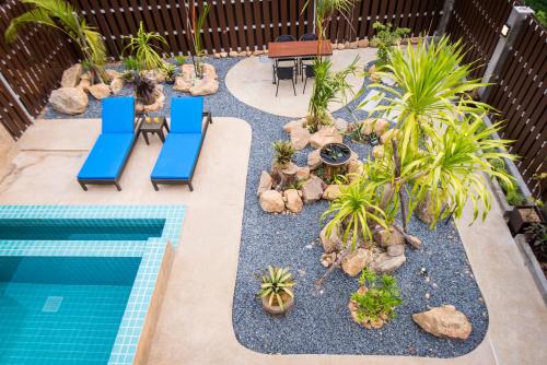a backyard with a swimming pool with blue chairs and plants at The Pearl Luxury Pool Villas in Ko Chang
