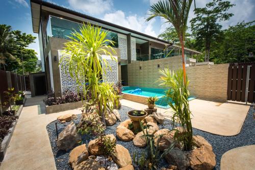 a garden with palm trees and a swimming pool at The Pearl Luxury Pool Villas in Ko Chang
