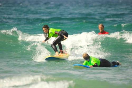 three people in the ocean on surfboards in the ocean at St Christopher's Inn Newquay in Newquay