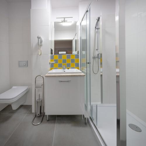 a white bathroom with a sink and a shower at Jubilat in Lądek-Zdrój