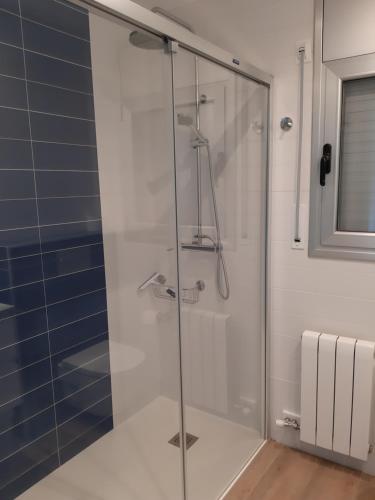 a glass shower in a bathroom with blue tiles at Apartament La Fosca Palamós in Palamós