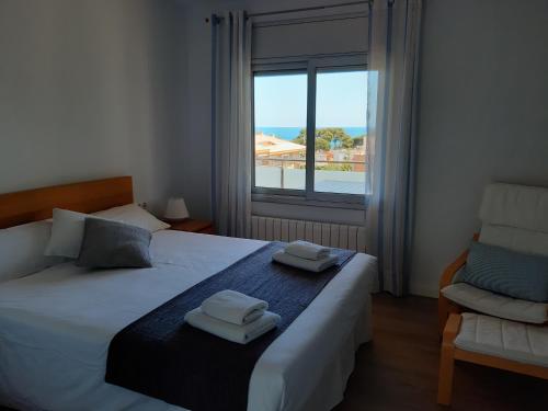 a bedroom with two beds and a window and a chair at Apartament La Fosca Palamós in Palamós