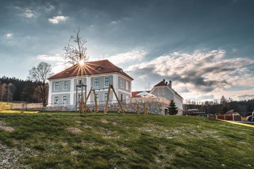 a house on a grassy hill with the sun shining on it at Aparthotel & Wellness Knížecí cesta in Horní Planá