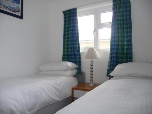 a room with two beds and a window with curtains at 151 Perran Sands in Perranporth