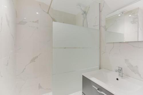 a white bathroom with a sink and a mirror at Design Apartment for 4 people between Louvre & Opera in Paris