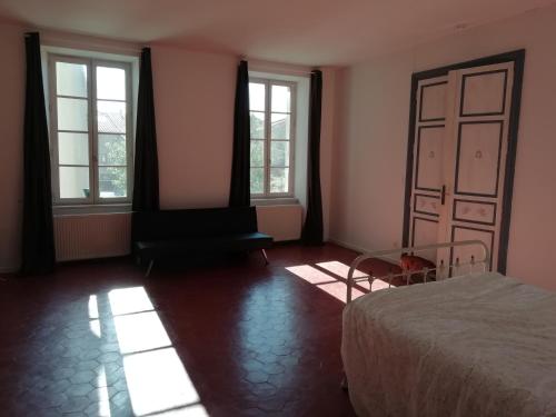 1 dormitorio con 1 cama y 2 ventanas en Les Colonnades, en Moussan